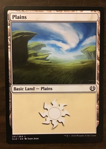 Basic land: Plains, vanilla-colored card with grass plains image and a sun logo underneath